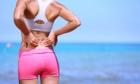 Una mujer en la playa se queja de dolor de espalda